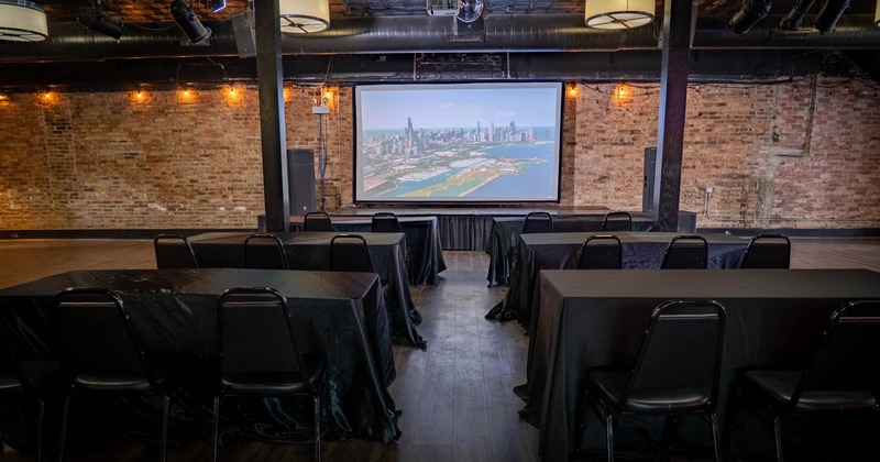 Event room with long tables facing a large projector screen
