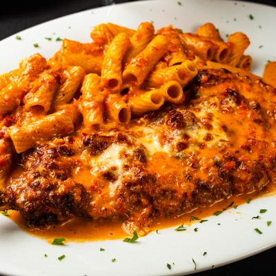 Chicken Parmesan served with rigatoni pasta and tomato sauce.