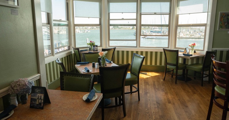 Interior, seating area, tables and chairs ready for guests, river view, hardwood floor