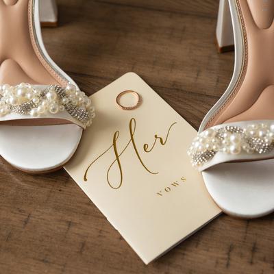 Bride's shoes and a ring placed on bride's vow book on a floor, close up