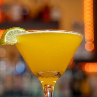 Cocktail in martini glass, garnished with lime half circle.