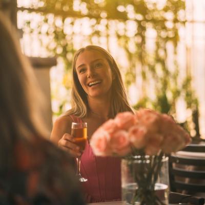 Customers enjoying a conversation over wine at a table with floral arrangement.