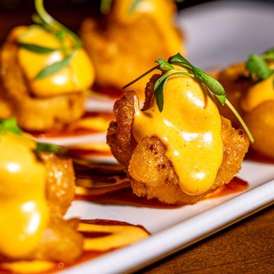 Buffalo cauliflower bites topped with sauce and fresh herbs.
