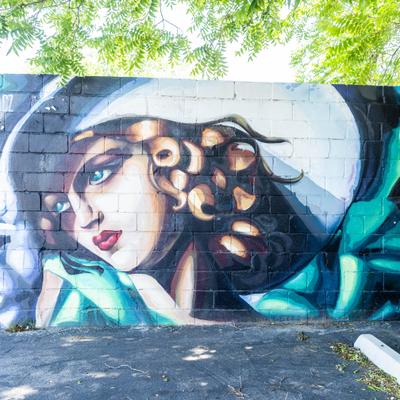 Mural on the brick wall depicting a woman with a hat.