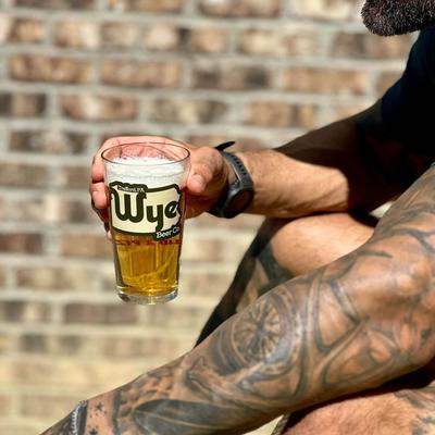 A tattooed person with a glass of beer.