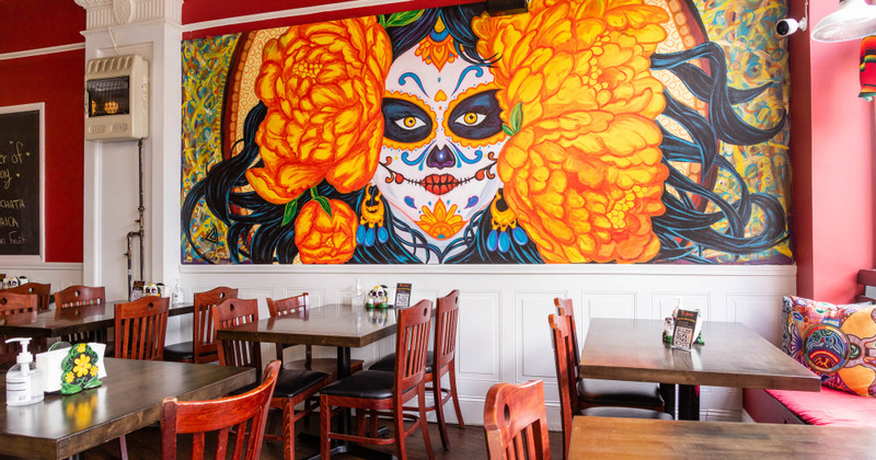 Interior, tables lined up by the wall with mexican mural