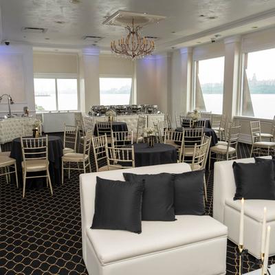 Banquet room with white seating and black pillows.