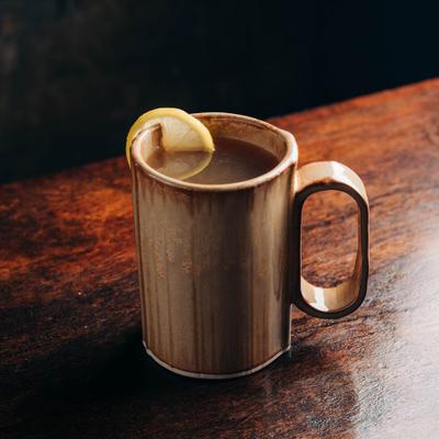 Detox tonic served in a r rustic mug, garnished with a lemon slice.