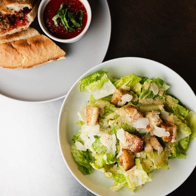 Meatball sandwich with marinara sauce and Caesar salad.