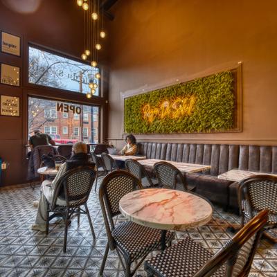 Interior with a mix of seating options and artificial green wall with a neon sign.