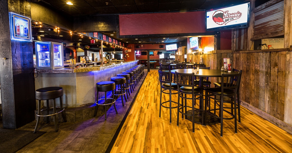 Interior, bar with stools on the left, round high seating tables with stools on the right