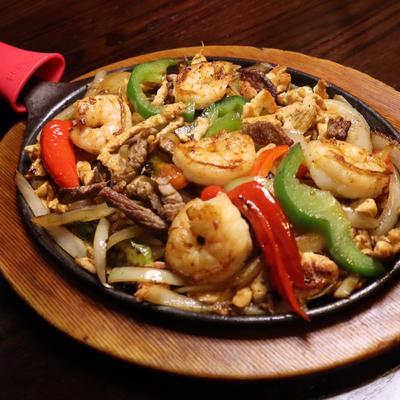 Beef, chicken, and shrimp fajitas, with grilled onion, and bell peppers.