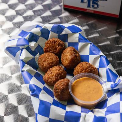 Fried crawfish balls served with dipping sauce on checkered paper.