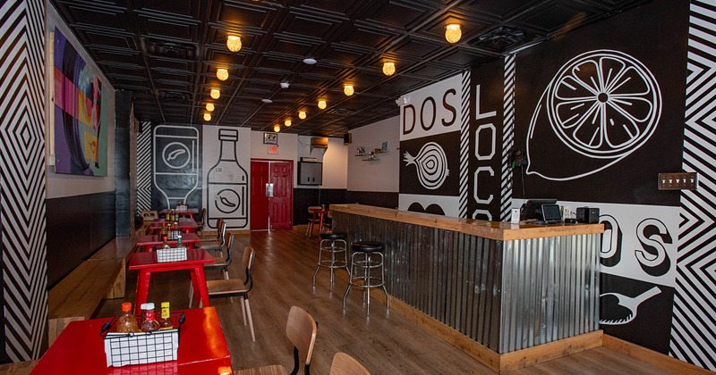 Interior of a modern restaurant with red tables, graphic wall art, and warm lighting