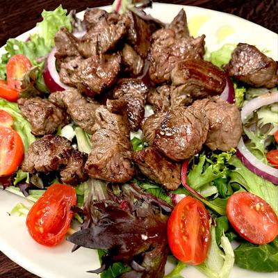 Grilled steak bites salad with mixed greens, cherry tomatoes, and red onions.