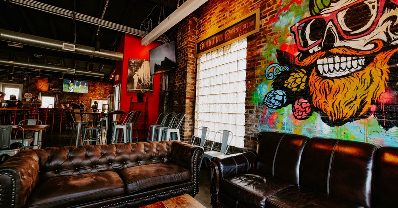 A bar interior - leather sofas, graffiti art and exposed brick walls, featuring industrial decor