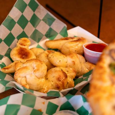 Garlic knots served with a side of marinara sauce.