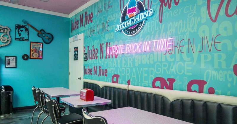 Interior of a retro-themed diner with turquoise and pink decor and neon signs