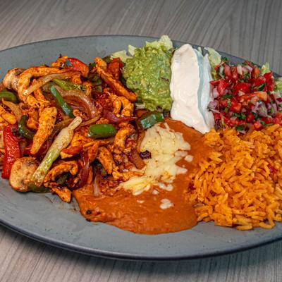 Chicken fajita lunch with sides of guacamole, sour cream, pico de gallo, rice, and beans.