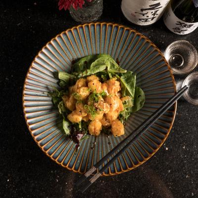 Rock shrimp tempura served with two glasses and two bottles of sake.