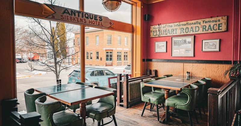 Interior dining area, wooden top tables with padded chairs, large shop window, street view