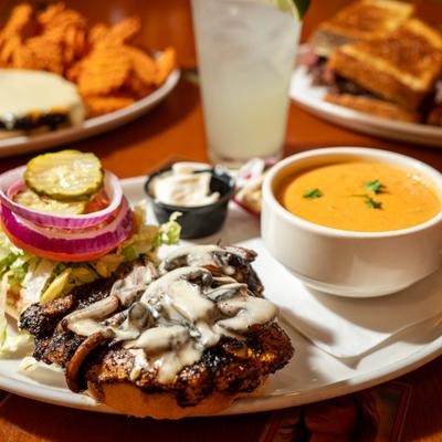 Blackened chicken sandwich topped with melted cheese and mushrooms, served with tomato soup.