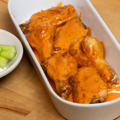 Six Bone in wings served with celery and a dipping sauce on the side.