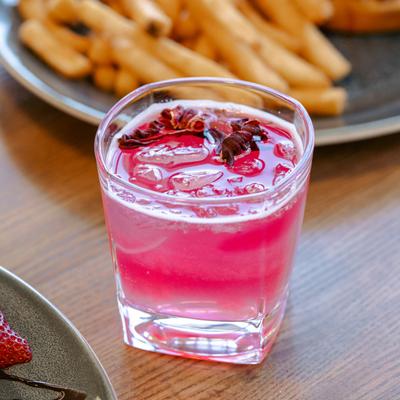 Pink Lady cocktail on a table with food, close up.