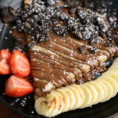 Strawberry Banana Oreo crepe topped with crumbled cookies and powdered sugar.