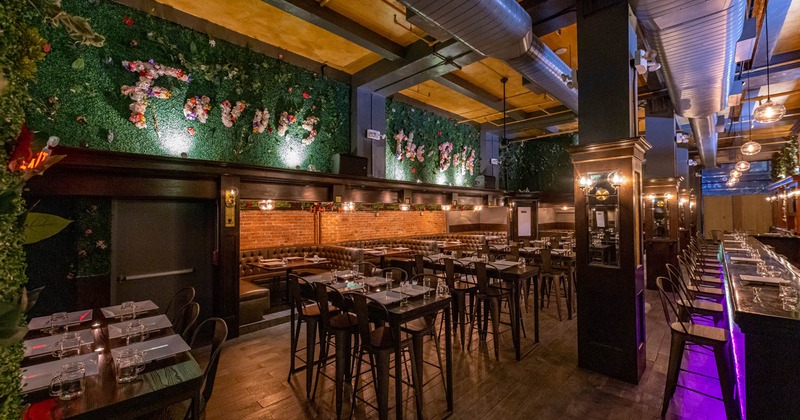 Interior, tables and chairs ready for guests, wood encased pillars, bar on the right