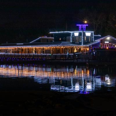 A brightly lit restaurant building at night, adorned with white and purple string lights.