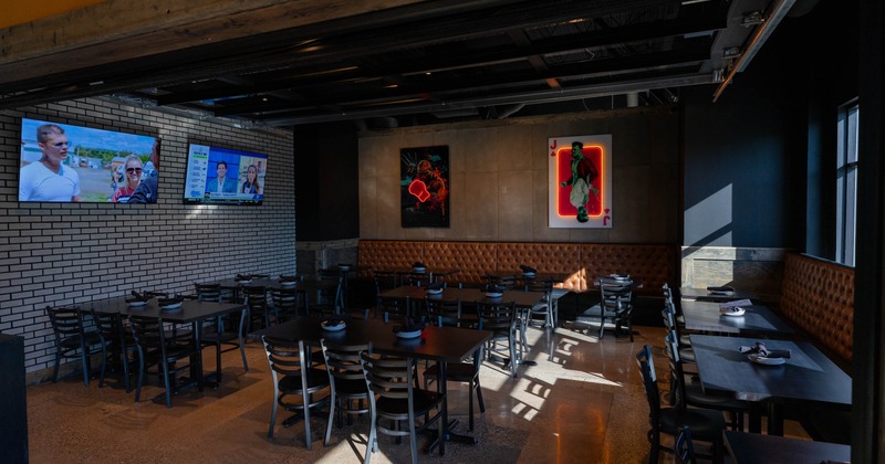 Interior of a modern restaurant with tables, televisions, and illuminated wall art