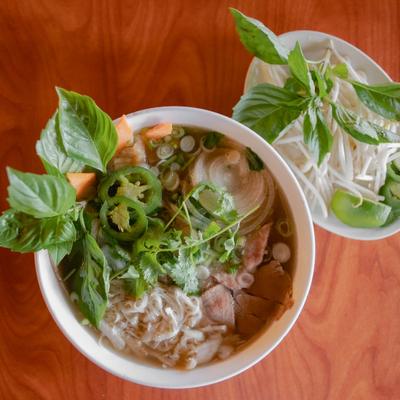 Vietnamese beef pho noodle soup with herbs and bean sprouts on the side.
