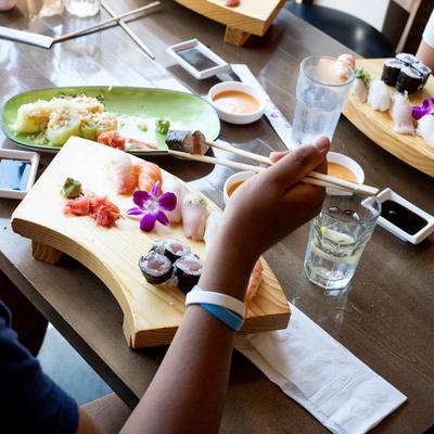 A hand holding chopsticks over a meal.