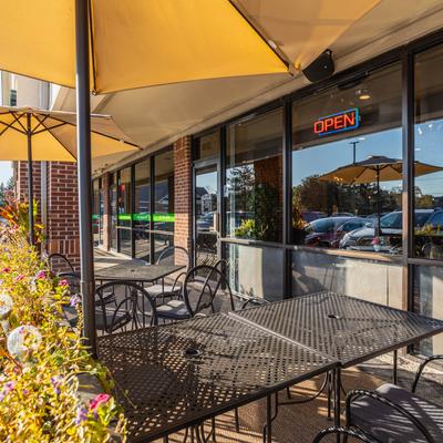 Exterior, seating area, tables and chairs with parasols and floral decoration.