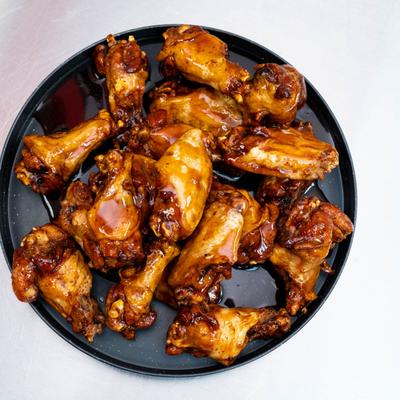A black plate with Traditional Teriyaki Wings, set on a white surface.