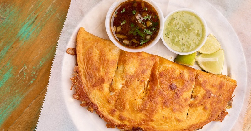 Quesabirria, served with lime, broth, and guacamole salsa