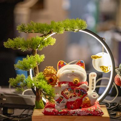 Decorative lucky cat and small bonsai tree figurines.