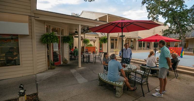 Outdoor patio with tables, chairs, and red umbrellas