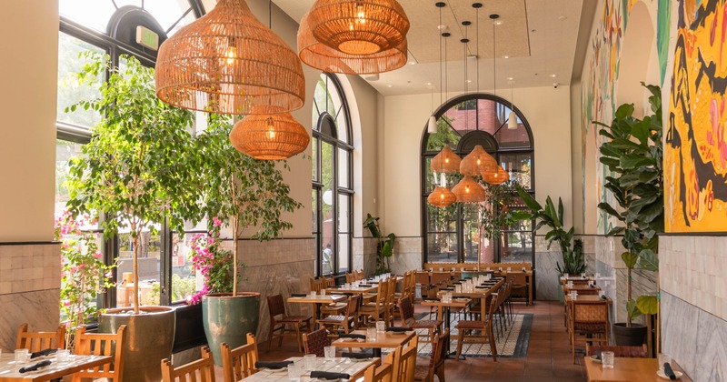 Interior, high ceiling dining room with large arched windows, wooden tables and chairs