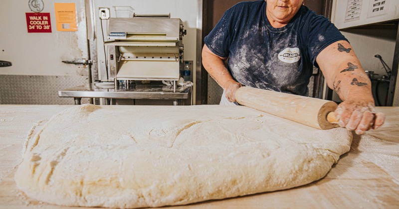 A baker spreading dough with pastry roller