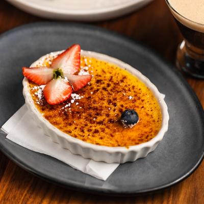 Creme Brulee garnished with sliced strawberry and a blueberry.