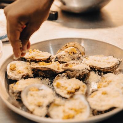 Charbroiled oysters being seasoned on a plate.