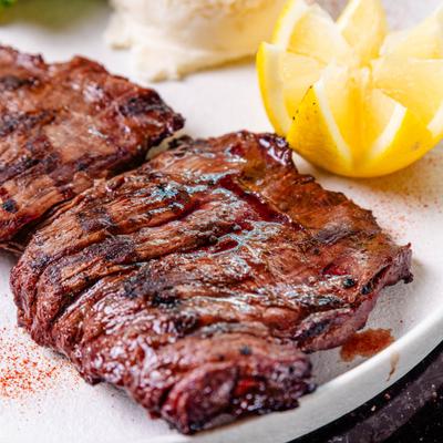 Grilled steak served alongside carved lemon, close-up.