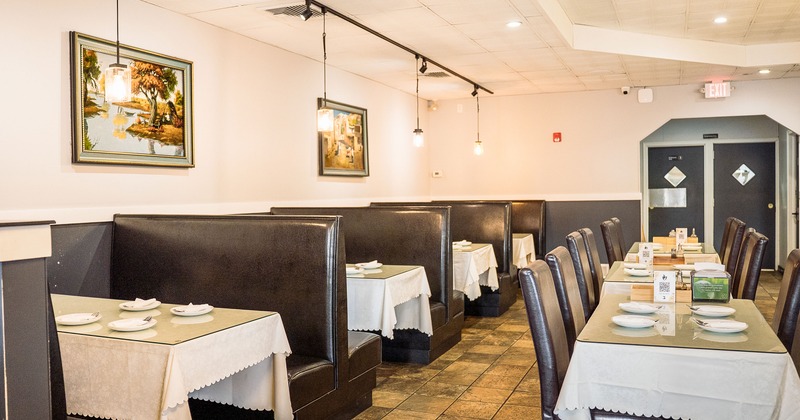 Spacious and cozy interior dining area with upholstered dining booths and tables set for guests