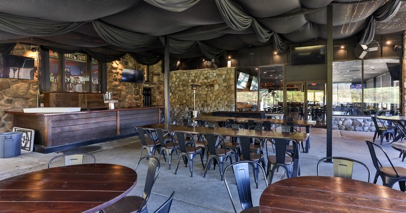 Indoor dining area with draped ceiling, stone walls, wooden tables, and metal chairs
