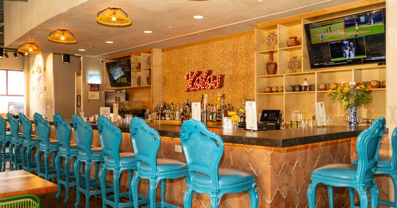 A colorful bar with turquoise stools, golden pendant lights