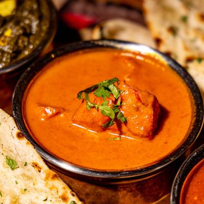 Butter Chicken served alongsdie naan bread and other dishes.