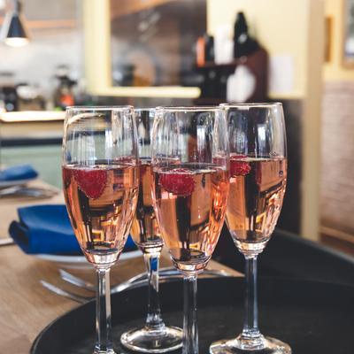 Pink champagne with raspberries served in glasses on a dining table.