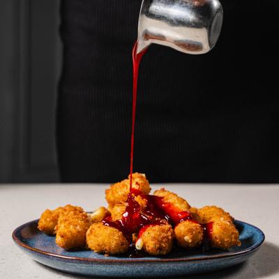 Red sauce being poured over cheese curds.